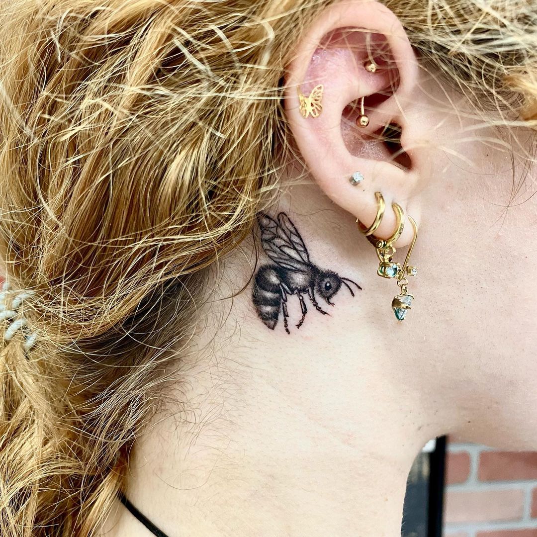 Tatuaje de abeja detrás de la oreja