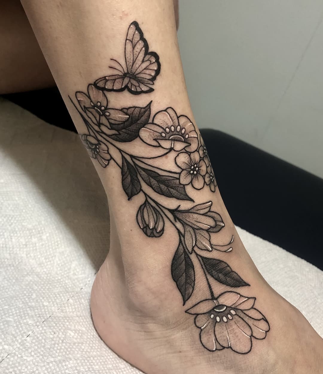 Tatuaje de un lirio con una mariposa sobre la pierna