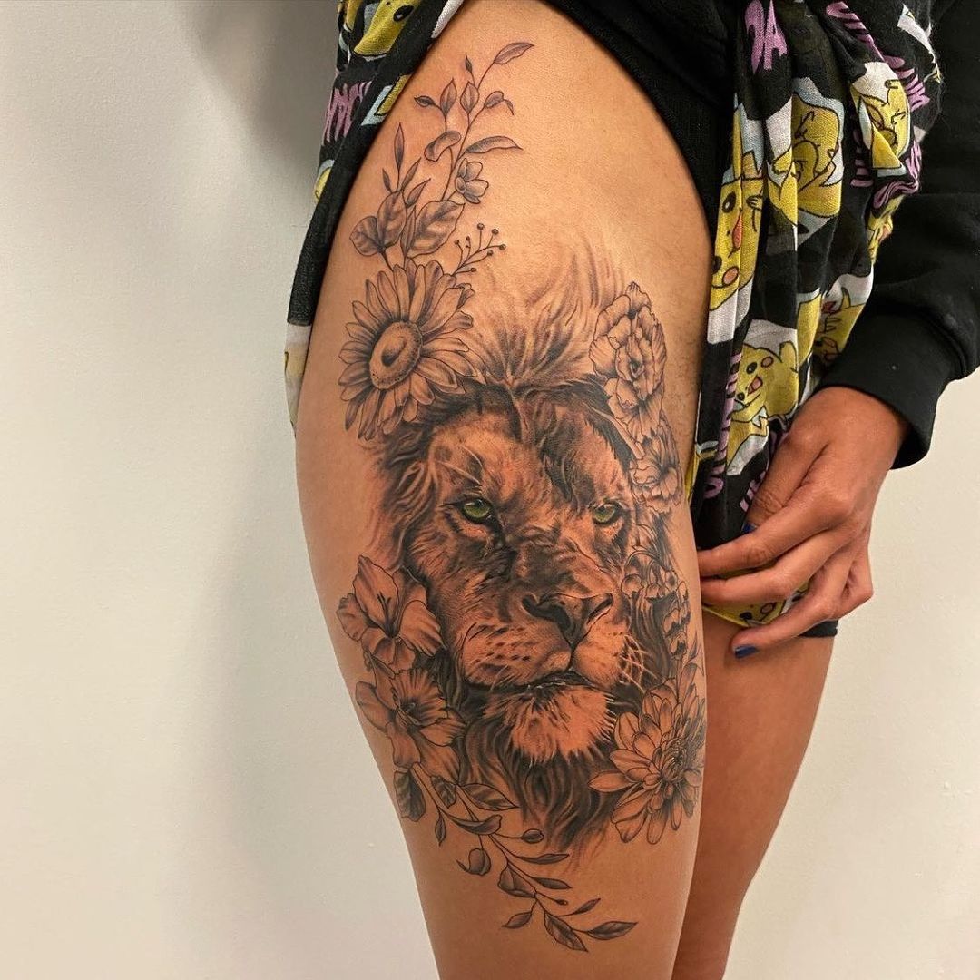 Tatuaje de un león en el muslo con girasoles