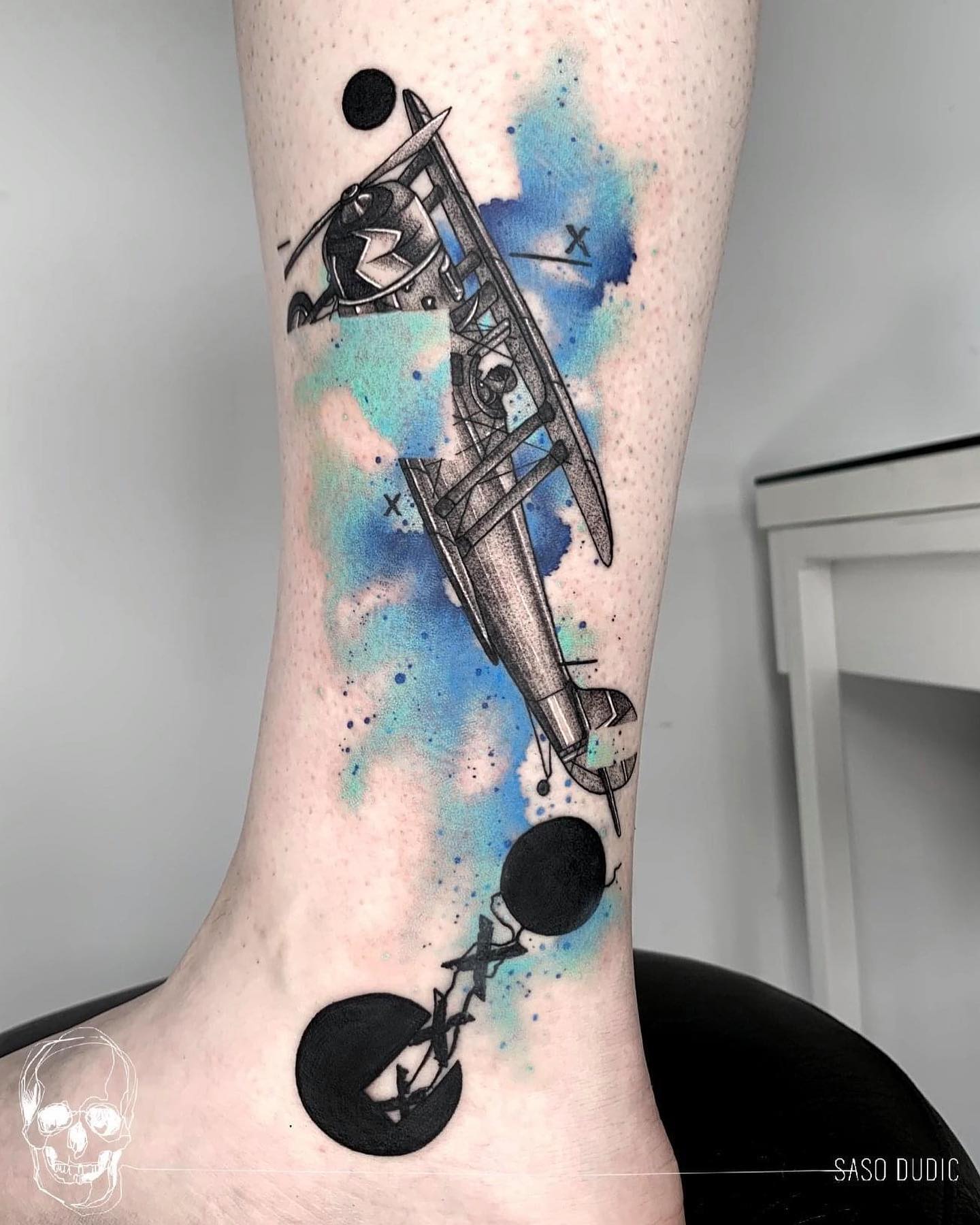 Tatuaje de un avión azul brillante en la pierna