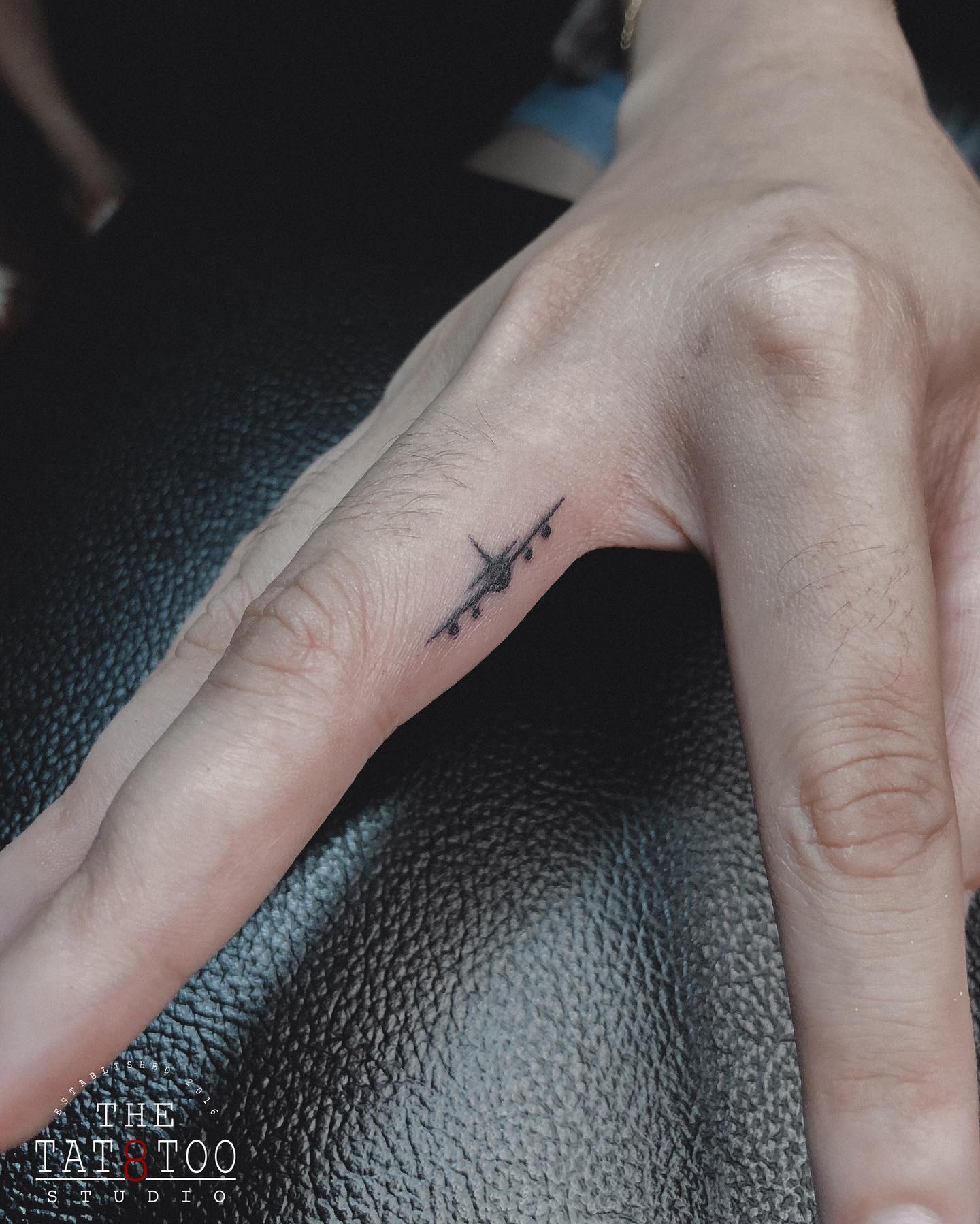 Tatuaje de un avión pequeño en el dedo