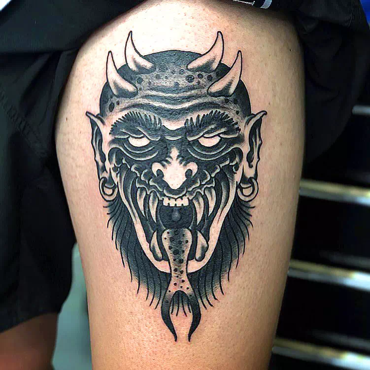 Tatuaje de un pequeño demonio negro en la pantorrilla
