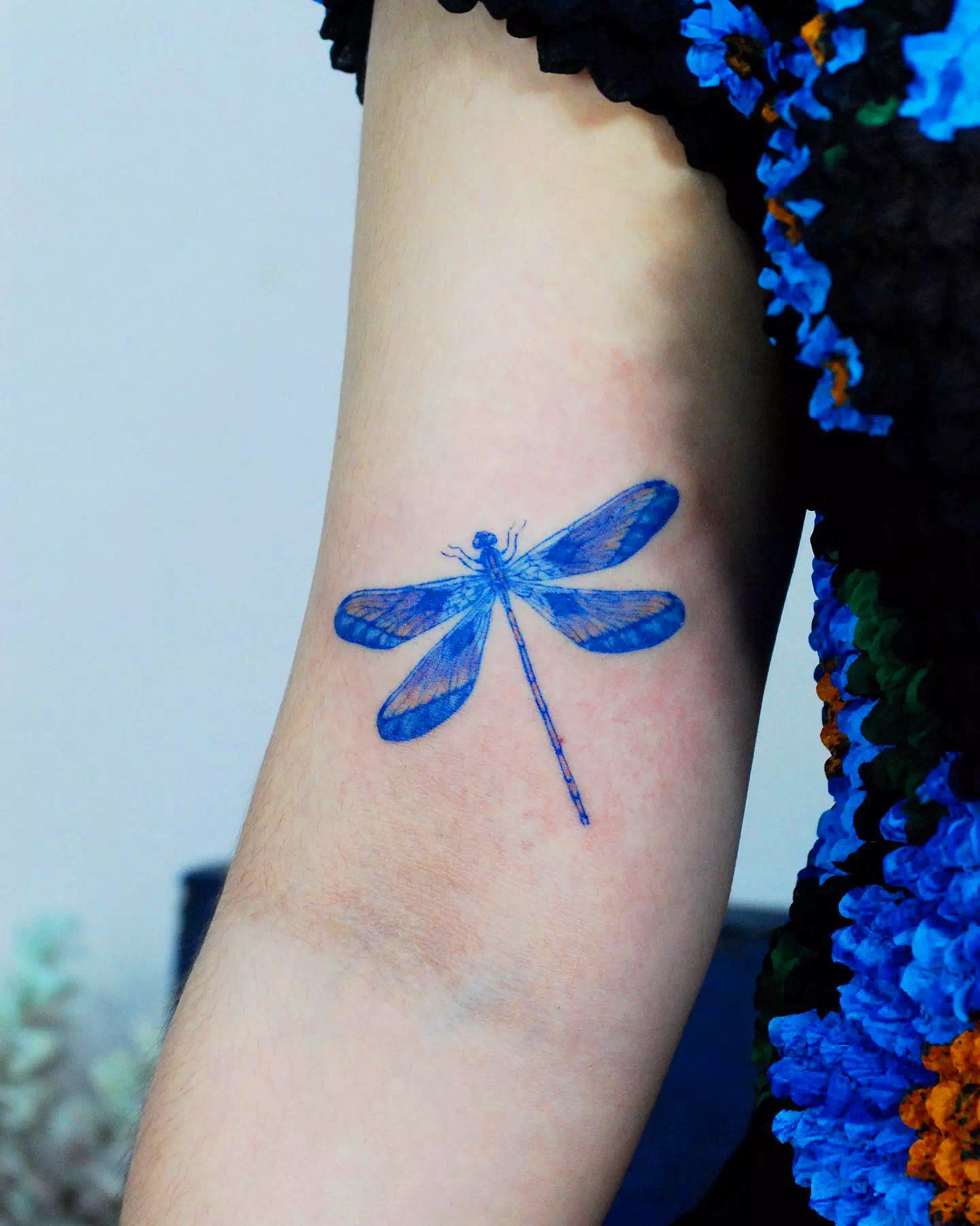 Tatuaje de libélula en el cuello azul