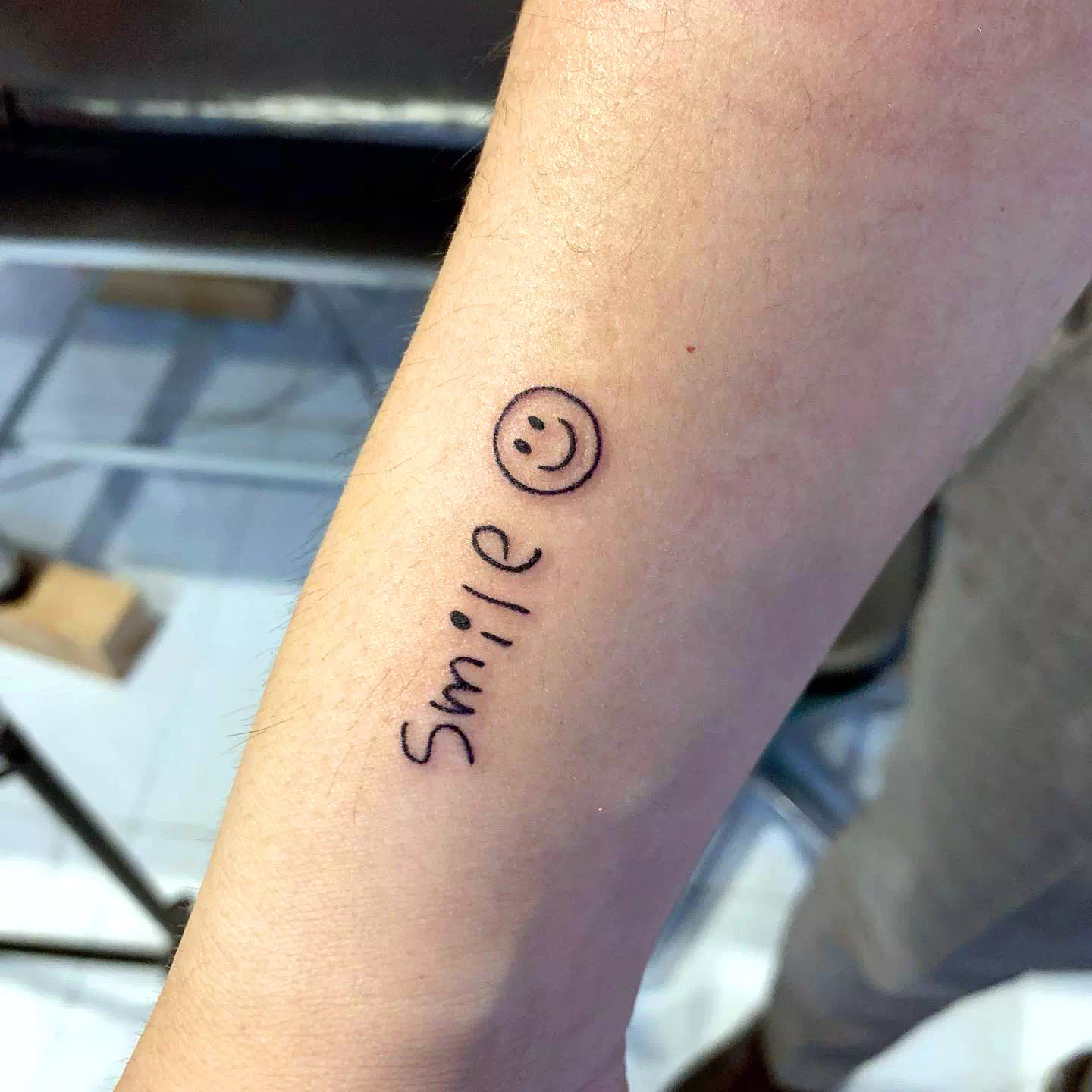 Tatuaje de una sonrisa optimista en el brazo