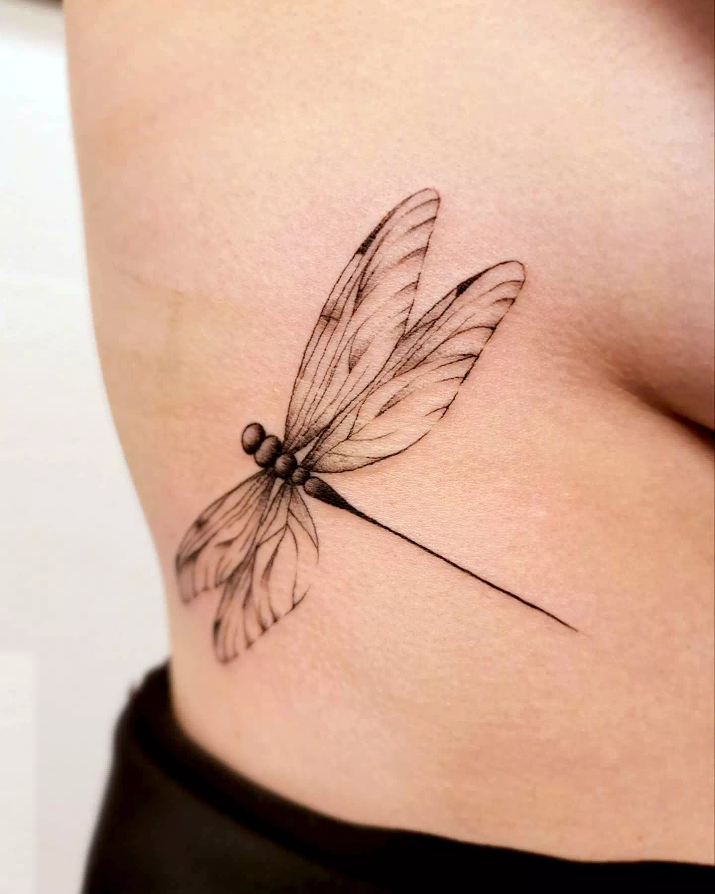 Tatuaje de libélula lateral en el estómago