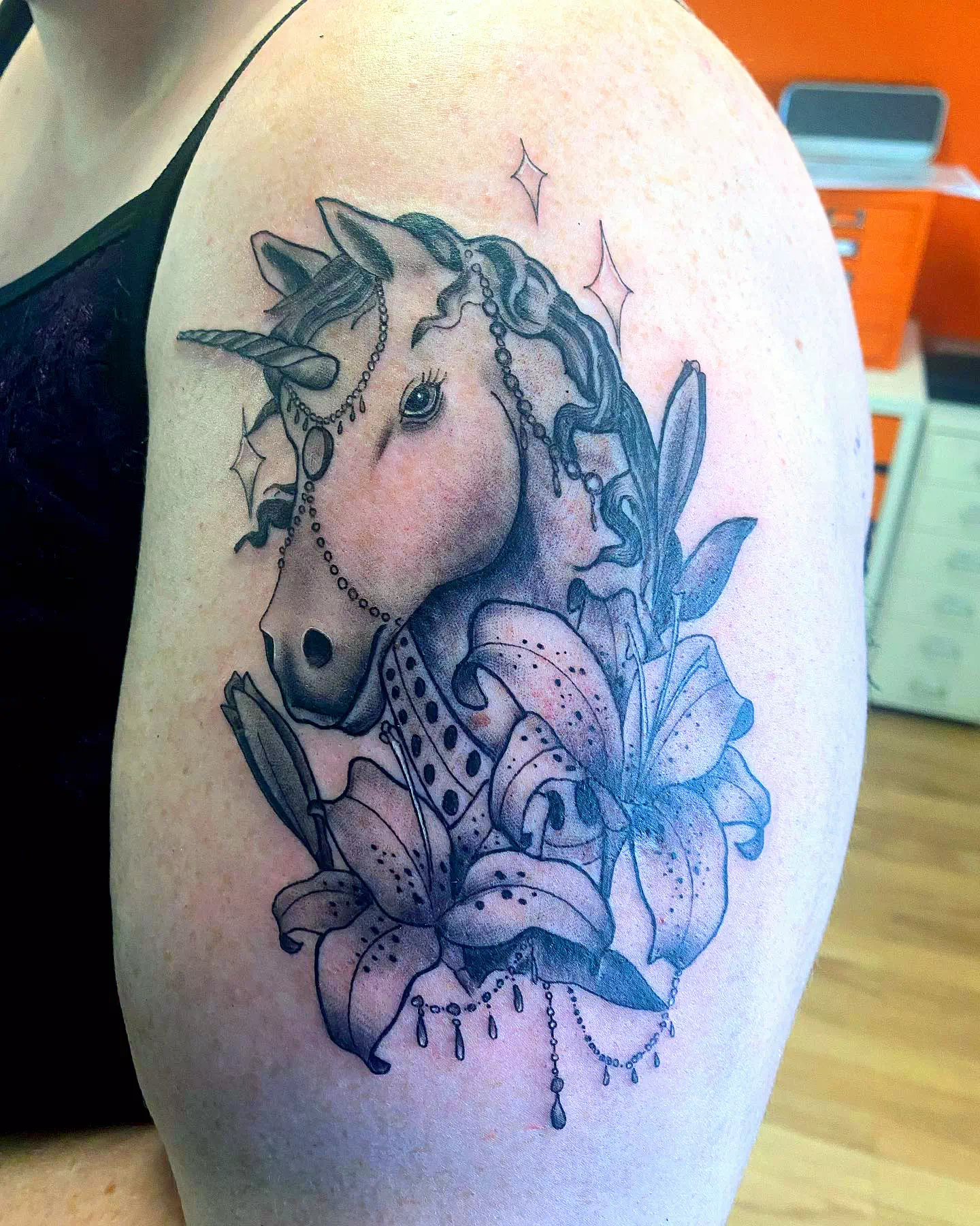 Schwarzes Einhorn Tattoo mit Blumen