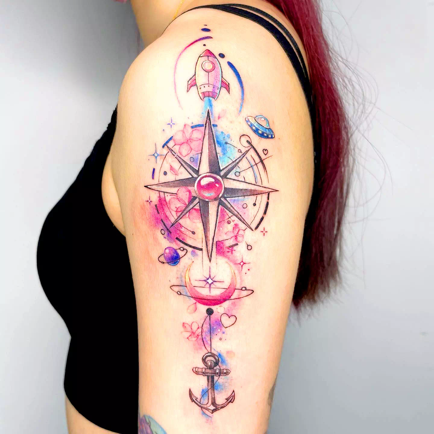 Tatuaje de una flecha con brújula azul en el antebrazo